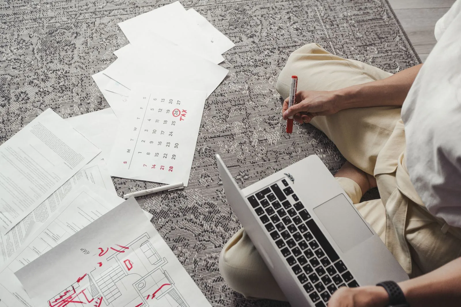 Mand planlægger ved sin bærbare computer med kalender og papirer