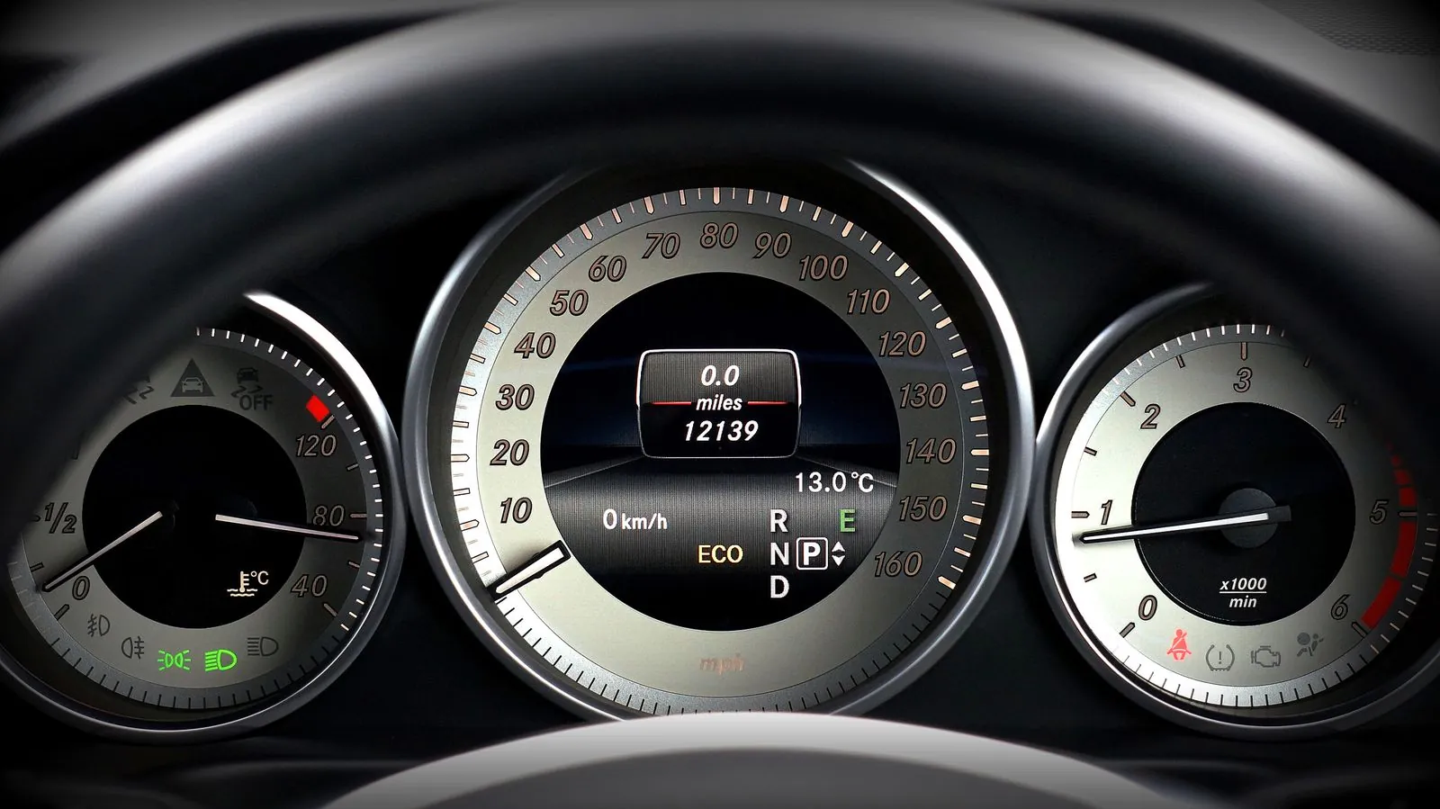 Bilens instrumentbræt med speedometer og kilometertæller